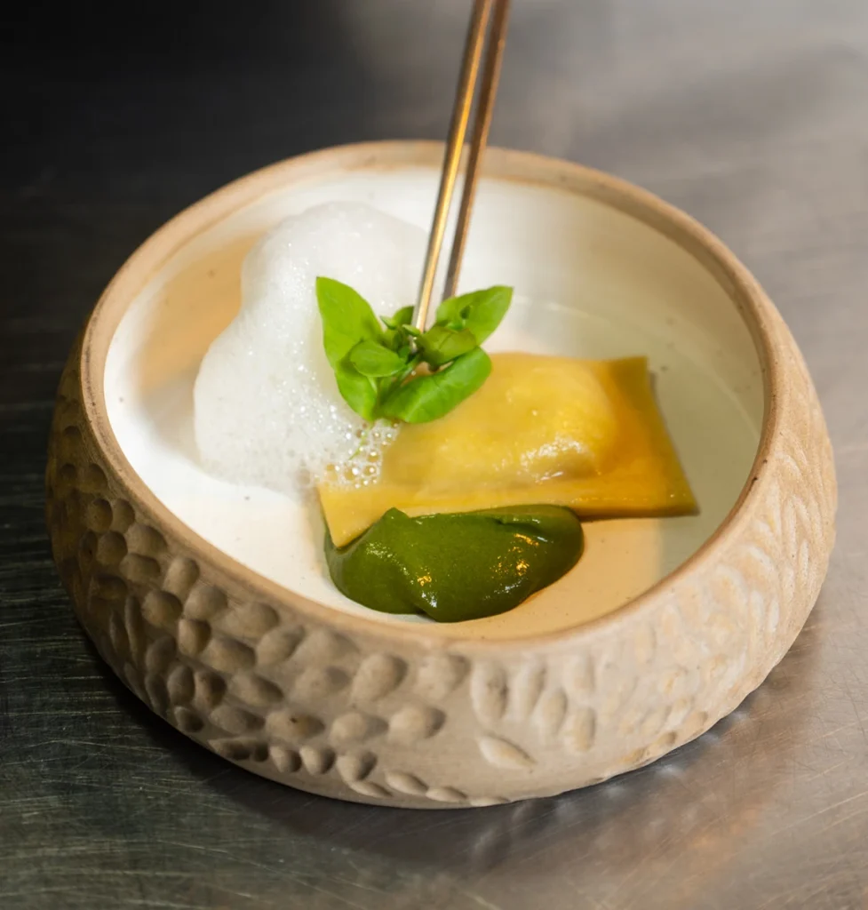 Raviolón de alcauciles con pesto y aire de limón